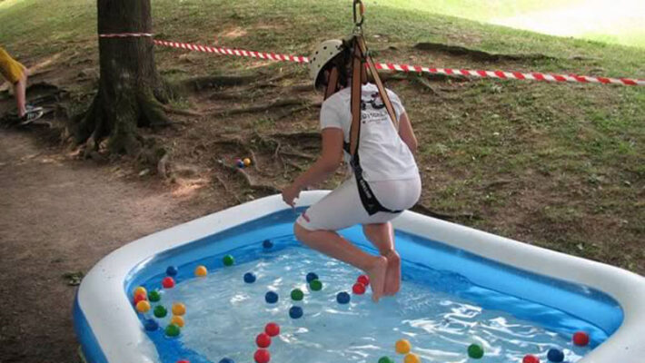 Teenieaktionstag: Ein Mädchen hängt am Seil über ein Planschbecken und versucht bunte Bälle herauszufischen